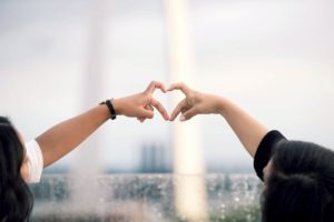 two friends touching fingers in the shape of a heart