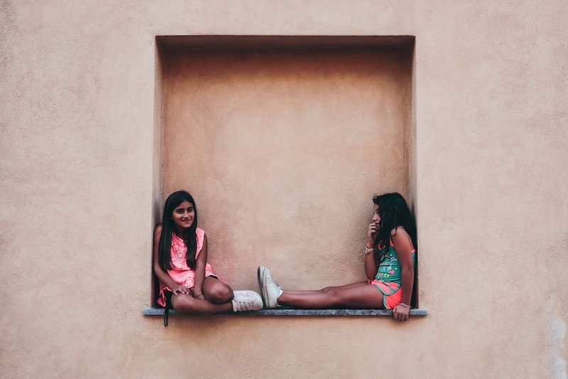 two kids sitting in a nook in the wall
