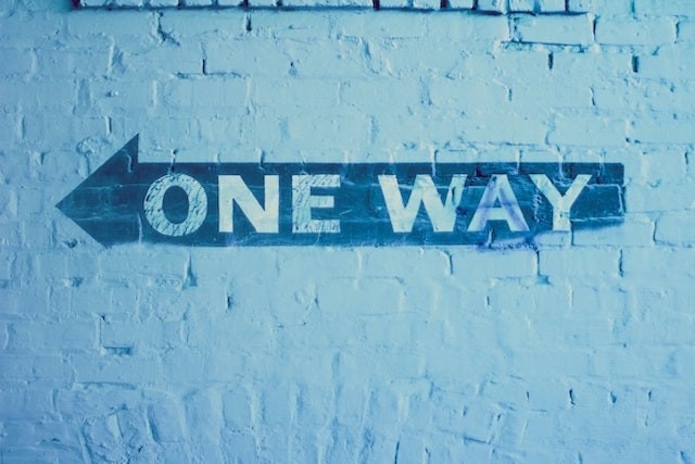 blue cement wall with blue arrow saying one way