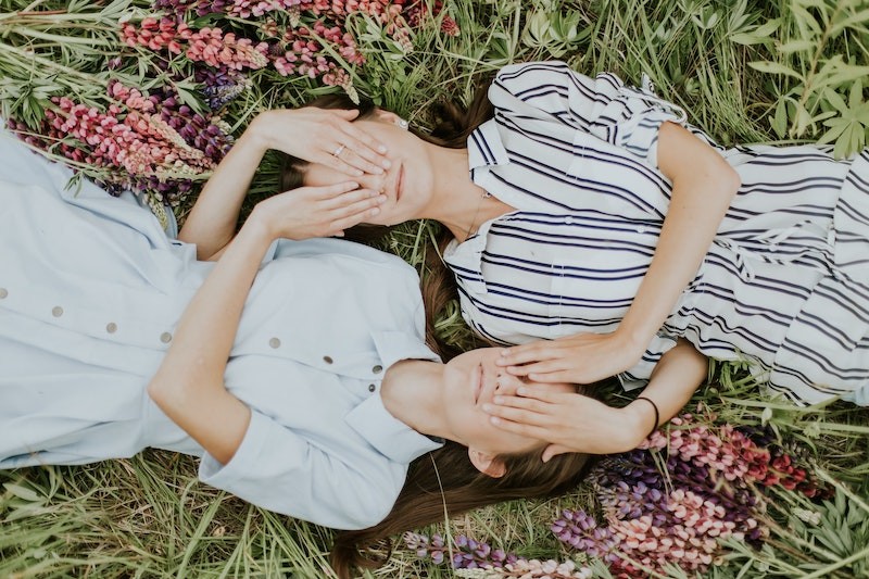 two friends laying next to each other with hands over eyes