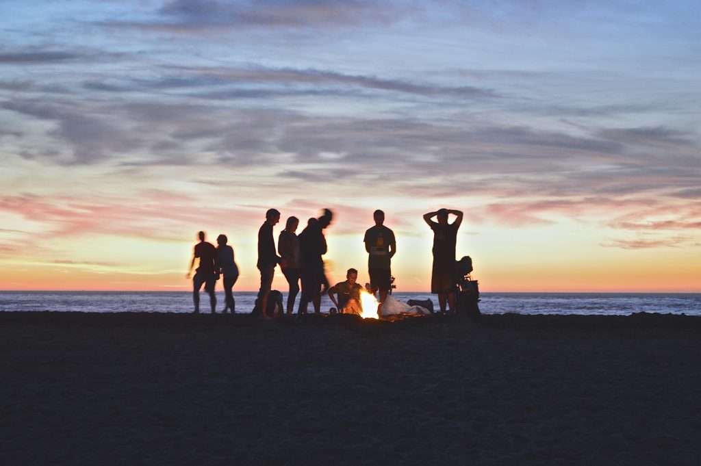 friends having a bonfire at sunset on the beach