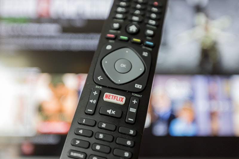 tv remote with netflix button and tv screen in background