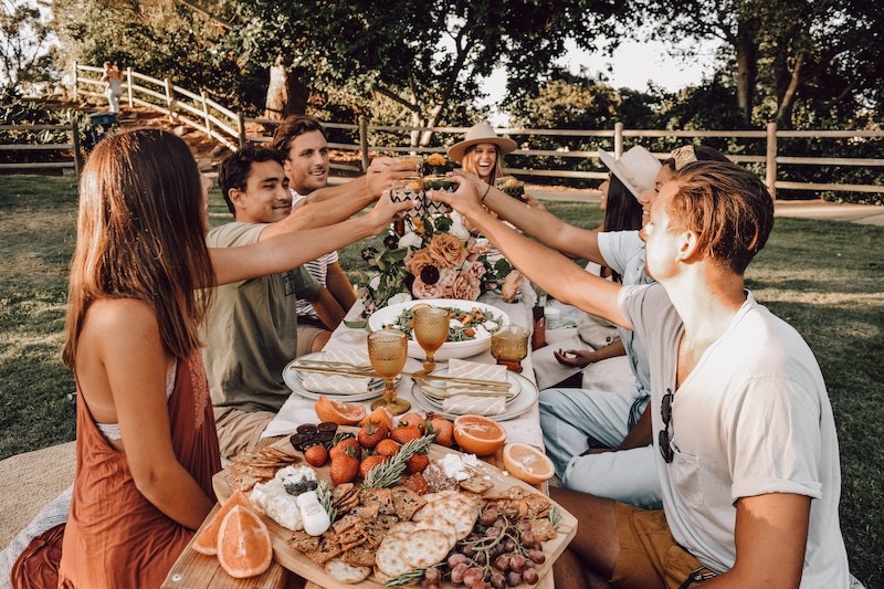 group of friends with long table of food doing a toast