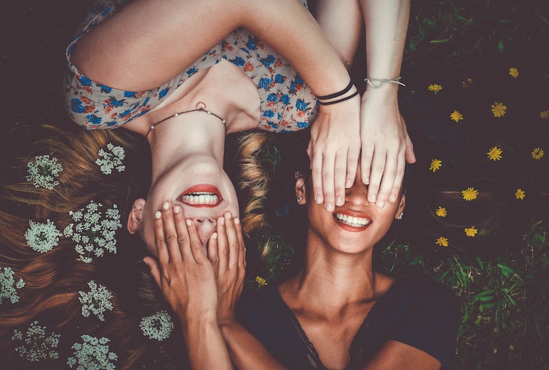 photograph of two women with hands over each other's eyes